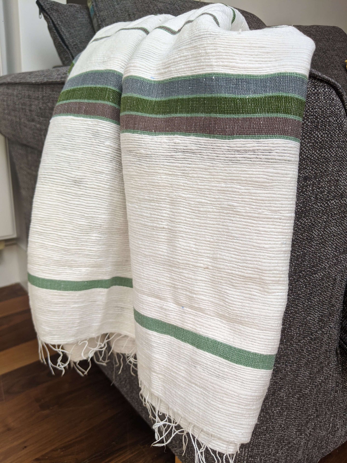 Handmade large thick cotton blanket throw draped over a sofa in green