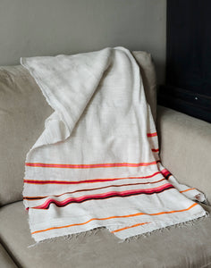 Handmade cotton orange and pink blanket laid on sofa