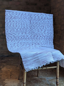 Handwoven handmade purple white cotton rug folded on chair