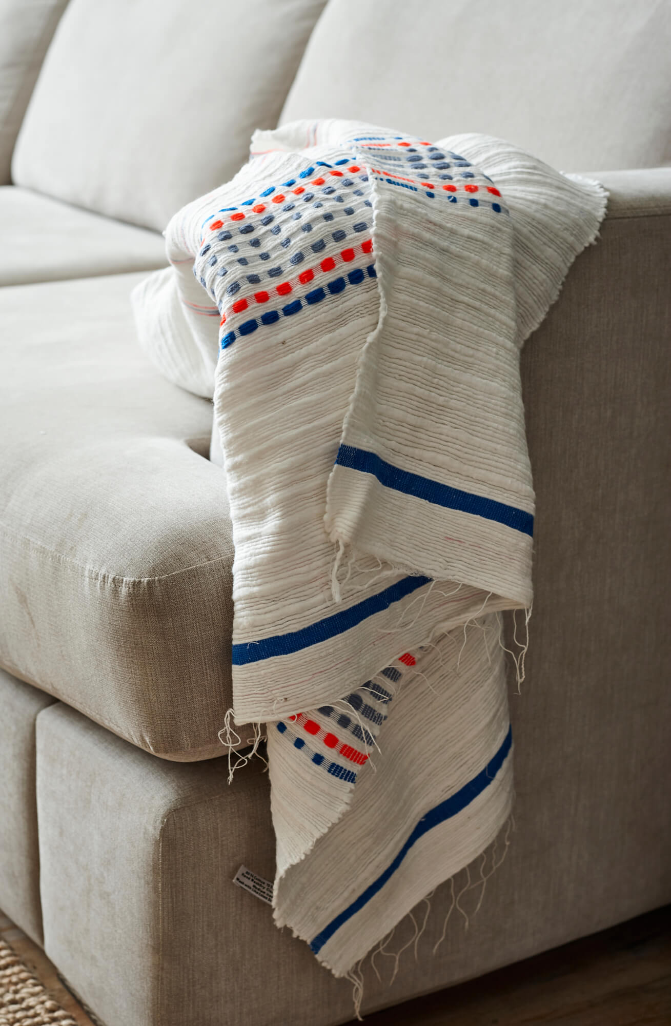Handmade white blue and orange cotton throw blanket on sofa