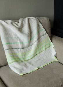 Handmade green and white cotton blanket laid on a sofa