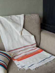 Handmade white orange and blue cotton throw blanket on a sofa